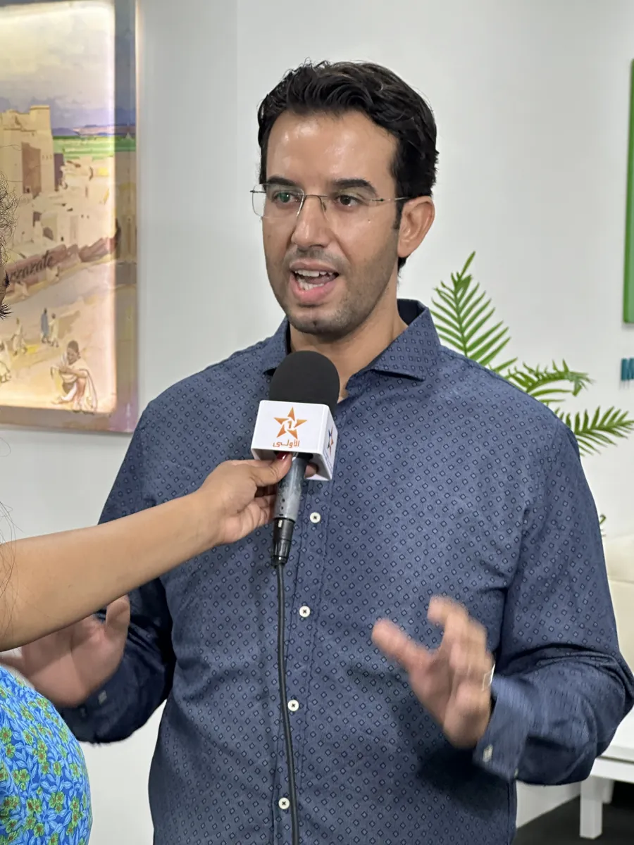 Abdelmajid Charrass répondant à une interview télévisée, micro tendu